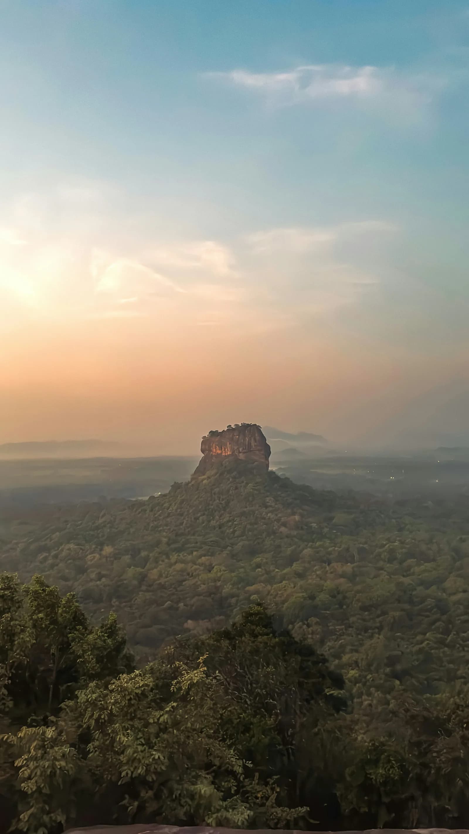 Golden tropical sunrise over the central plains and Sigiriya Rock from the summit of Pidurangala, Sri Lanka.