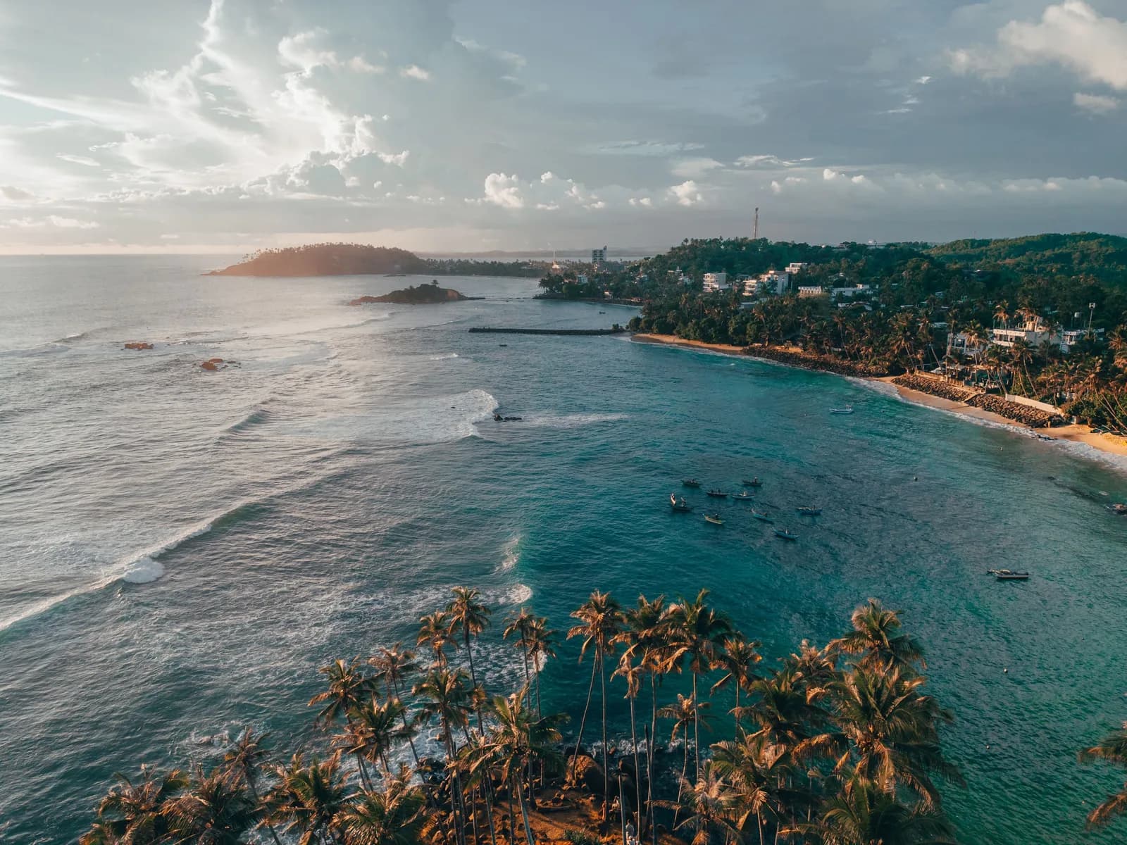 Panoramic sandy coastline stretching into the horizon with foamy breakers.